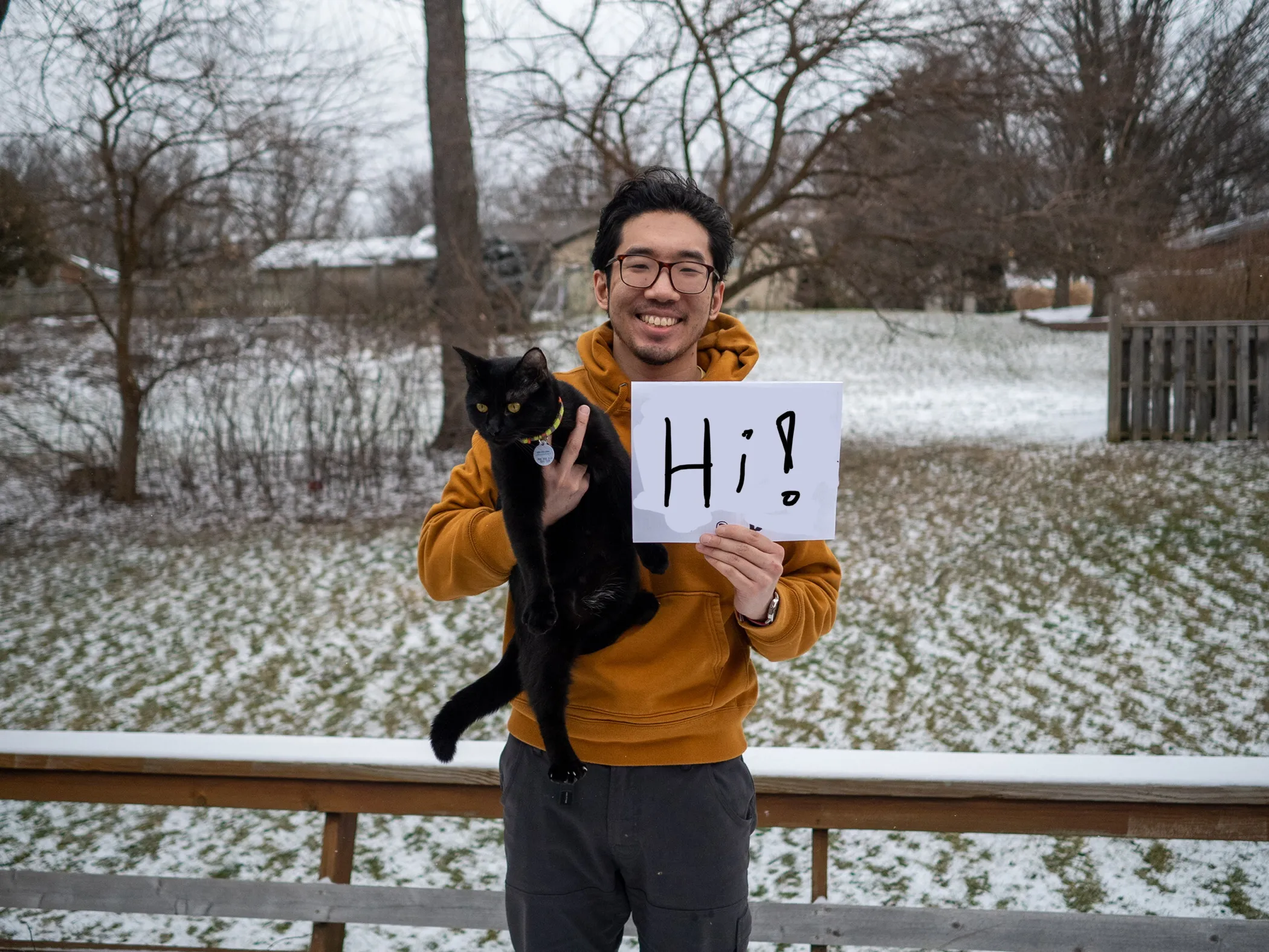 Me holding my cat Moses, holding up a sign that says Hi! on it.